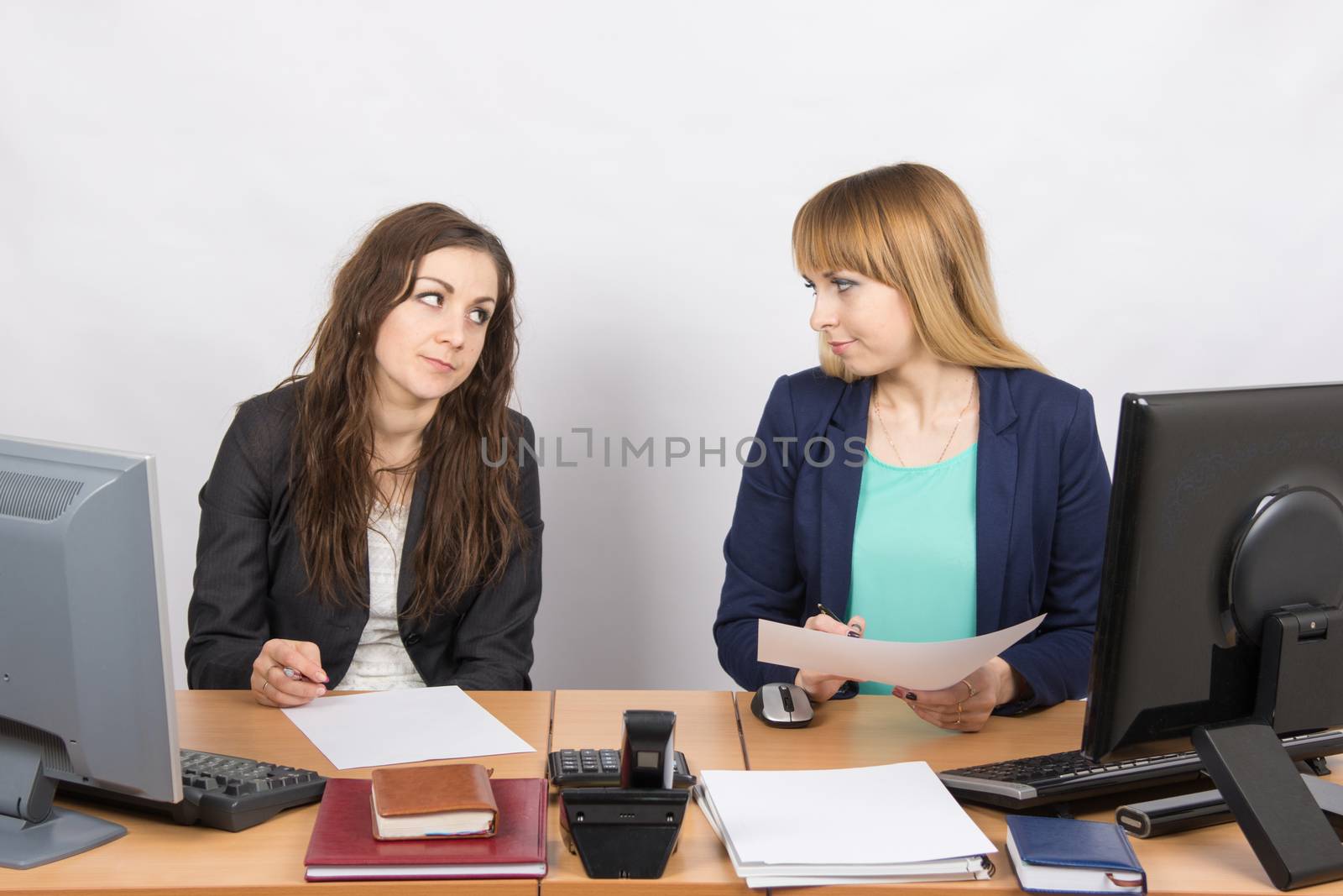 Two office employee sitting at a desk and a hostile look at each other