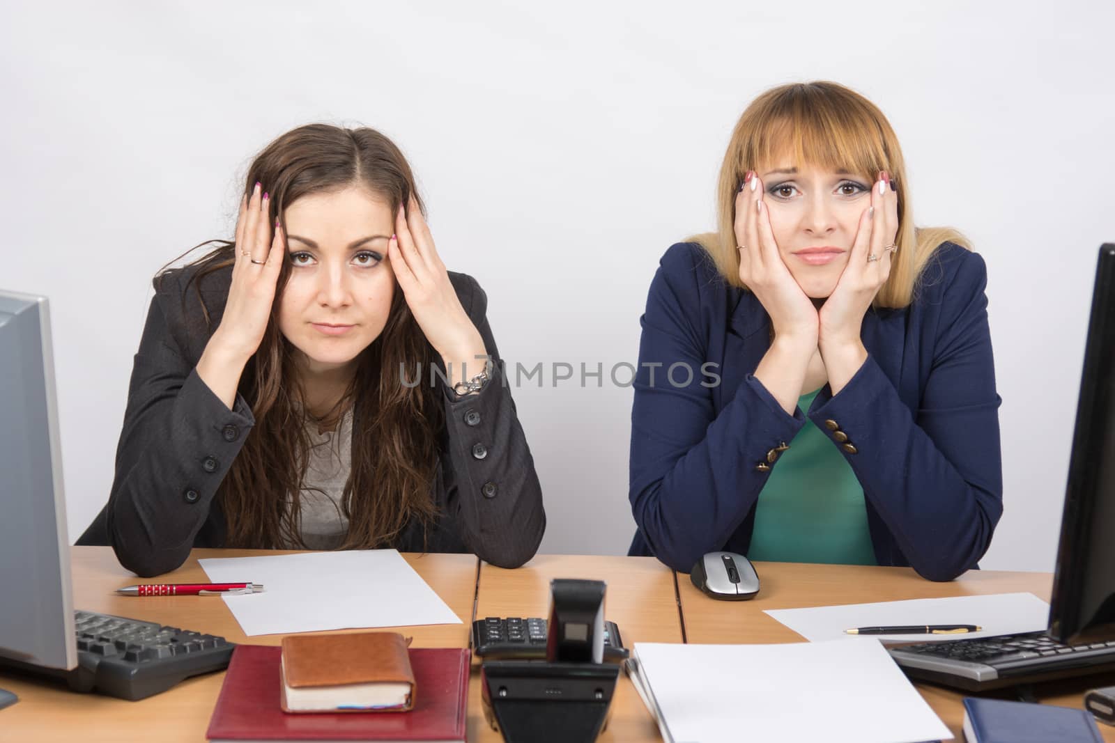 Two office employee sitting with depressed and frightened look