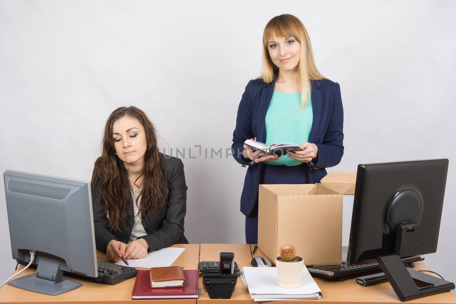 An employee in the office happily puts things out of the box next to a colleague