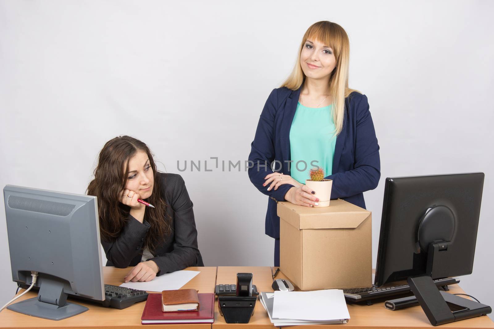 New employee in the office happily keeps things close sad colleague