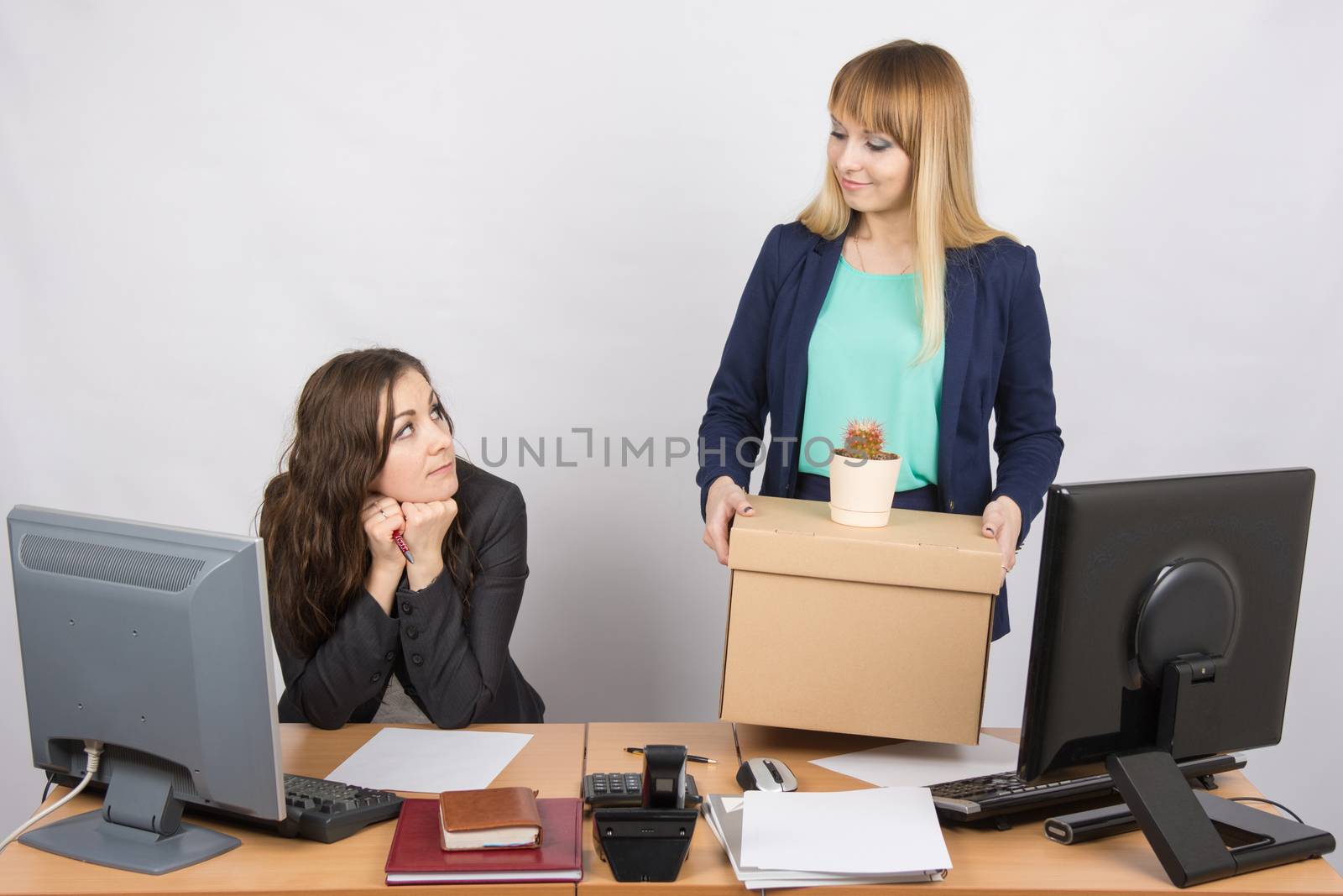 The girl in the office happily holding bags and looking at colleague