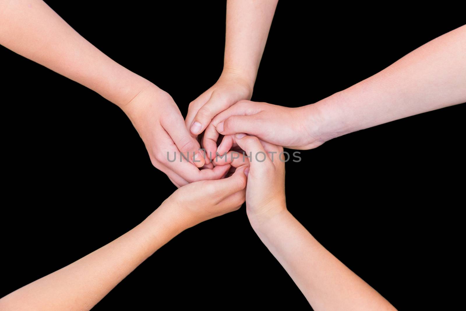 Five children's arms with hands entwined isolated on black background
