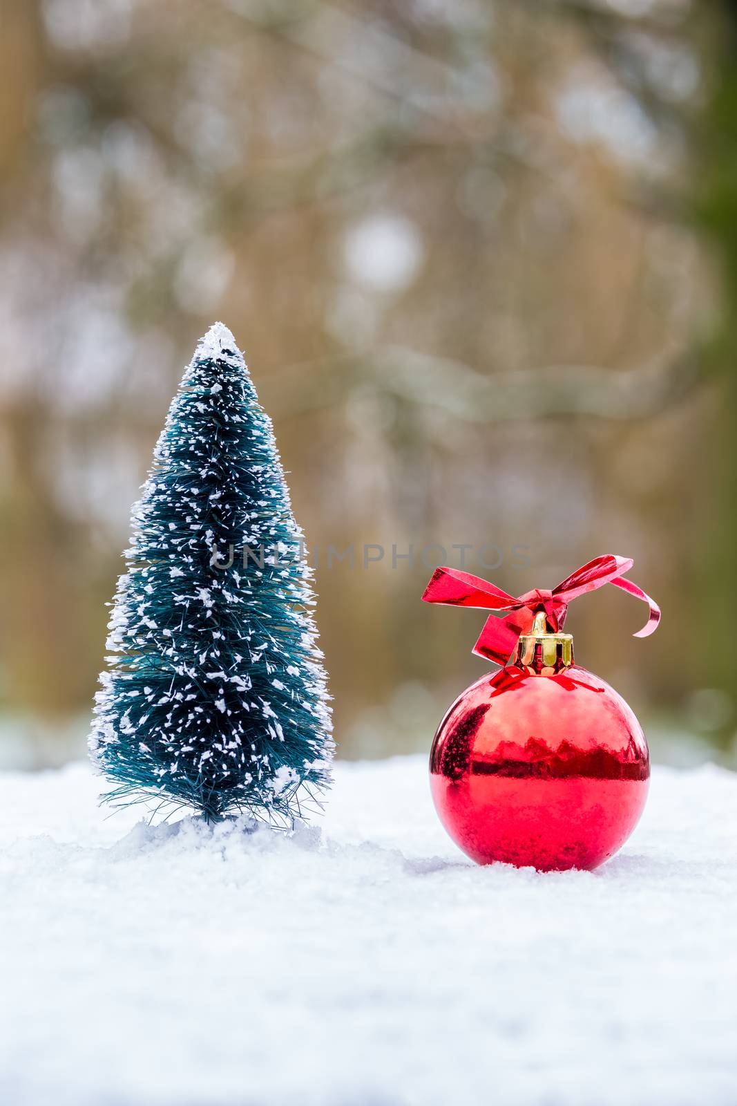 Little christmas tree with red bauble outdoors in white snow