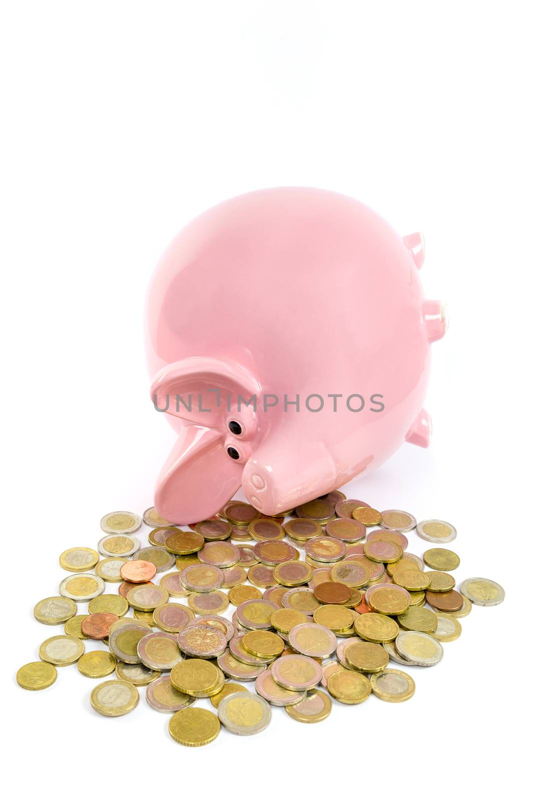 Lying pink piggy bank with pile of euro coins isolated on white background