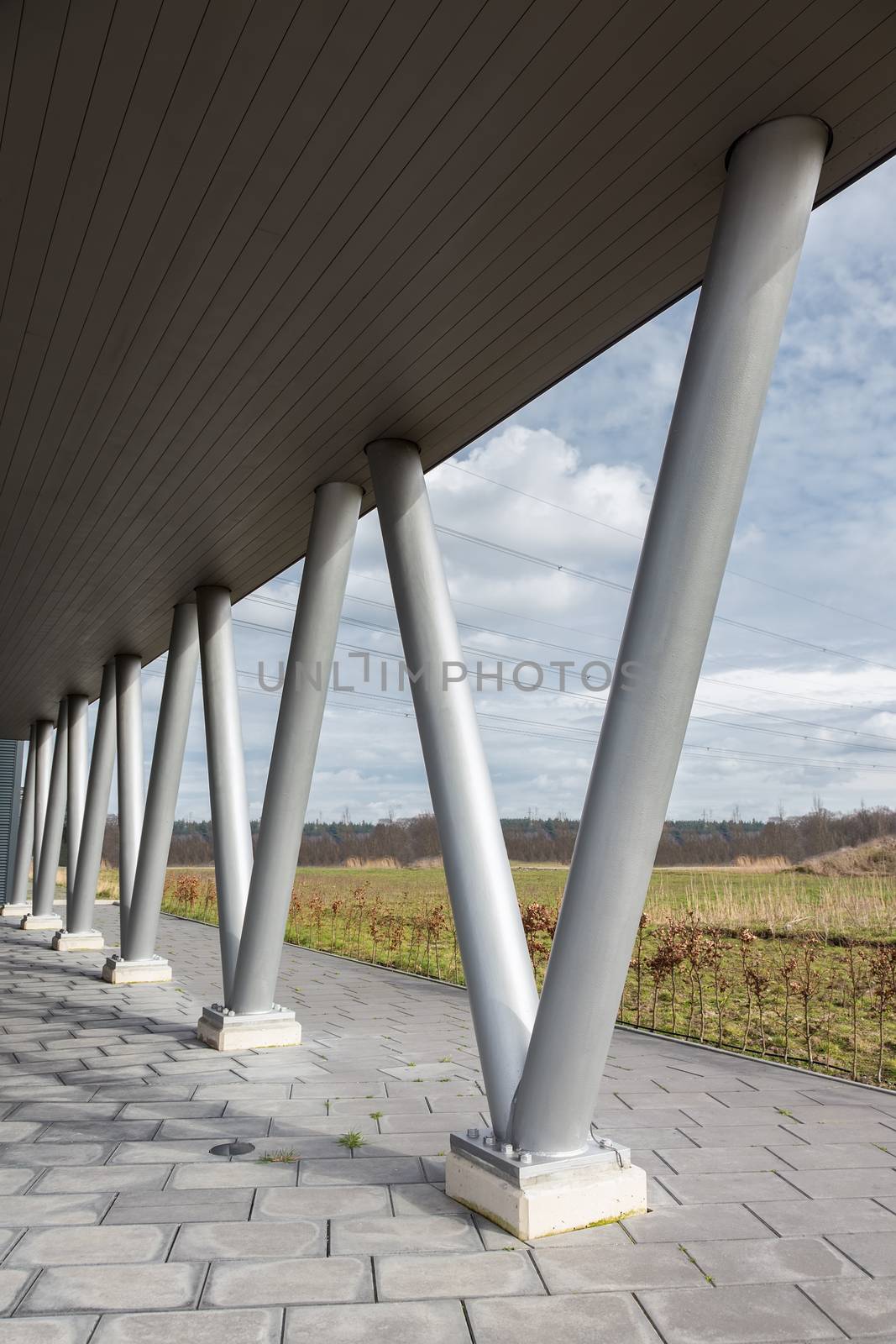 V- shaped metal pillars under roof of building by BenSchonewille