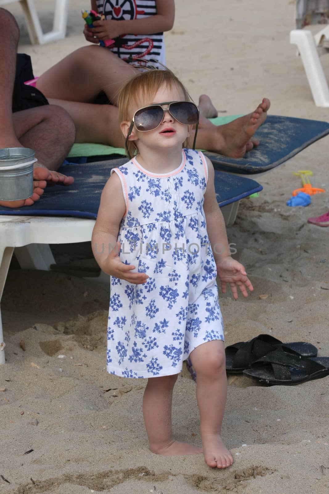 Baby girl with big glasses  posing on the beach
