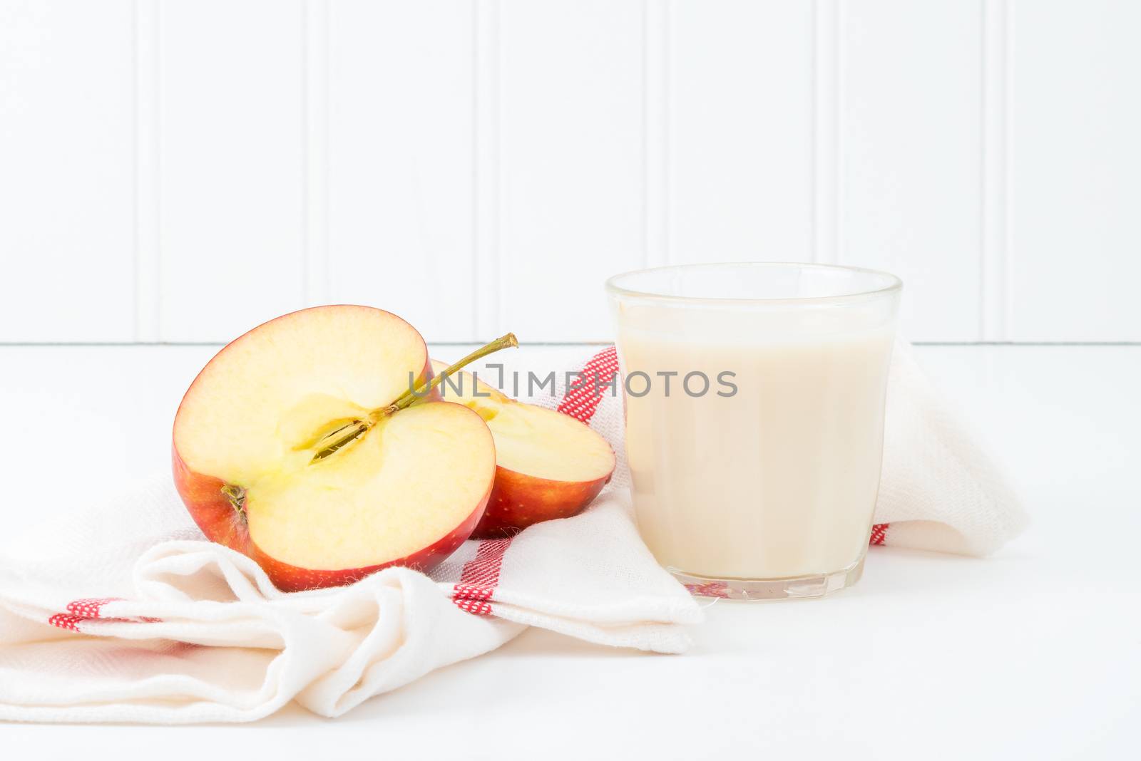 Snack of sliced fresh red apple and a glass of cold milk.