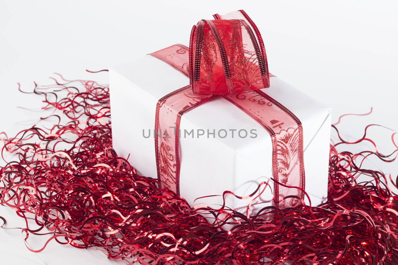 Present in white paper with red ribbon and red garlands isolated on white background