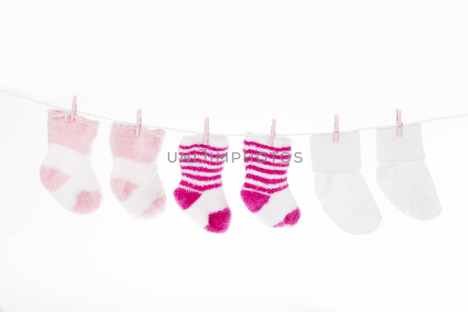 Pink and white baby socks on clothesline, isolated on white background