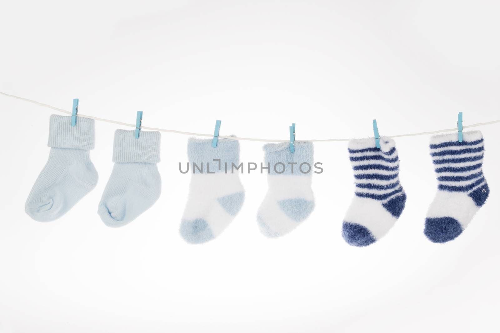 Blue and white baby socks on clothesline, isolated on white background