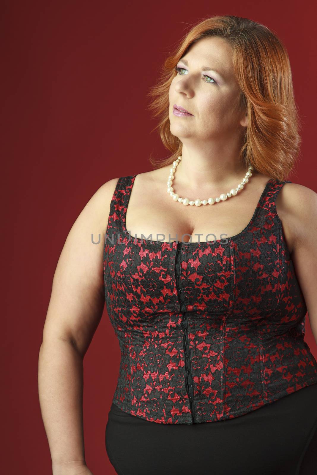 woman in her fortie wearing a red corset looking top the left