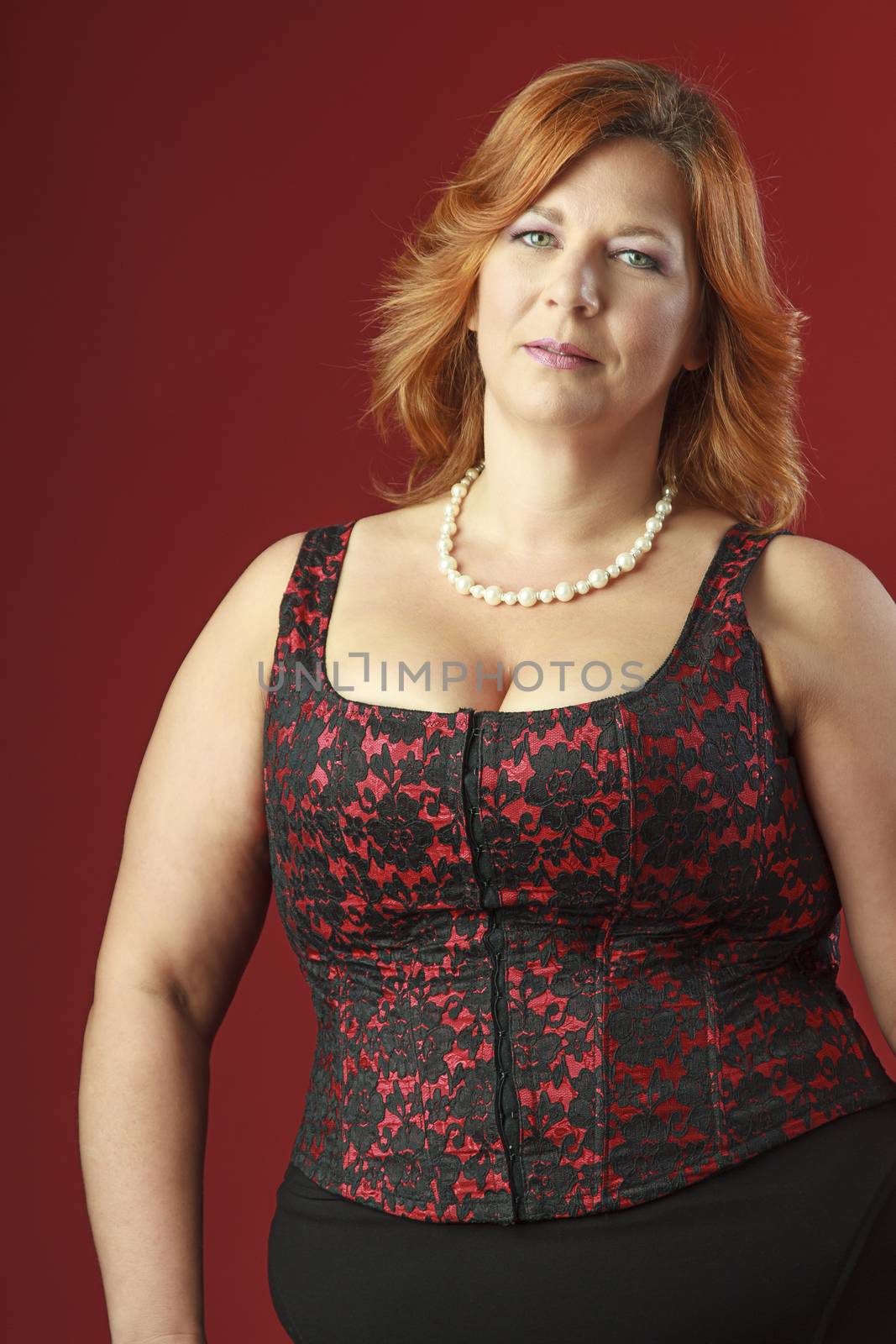 woman in her fortie wearing a red corset against a red background