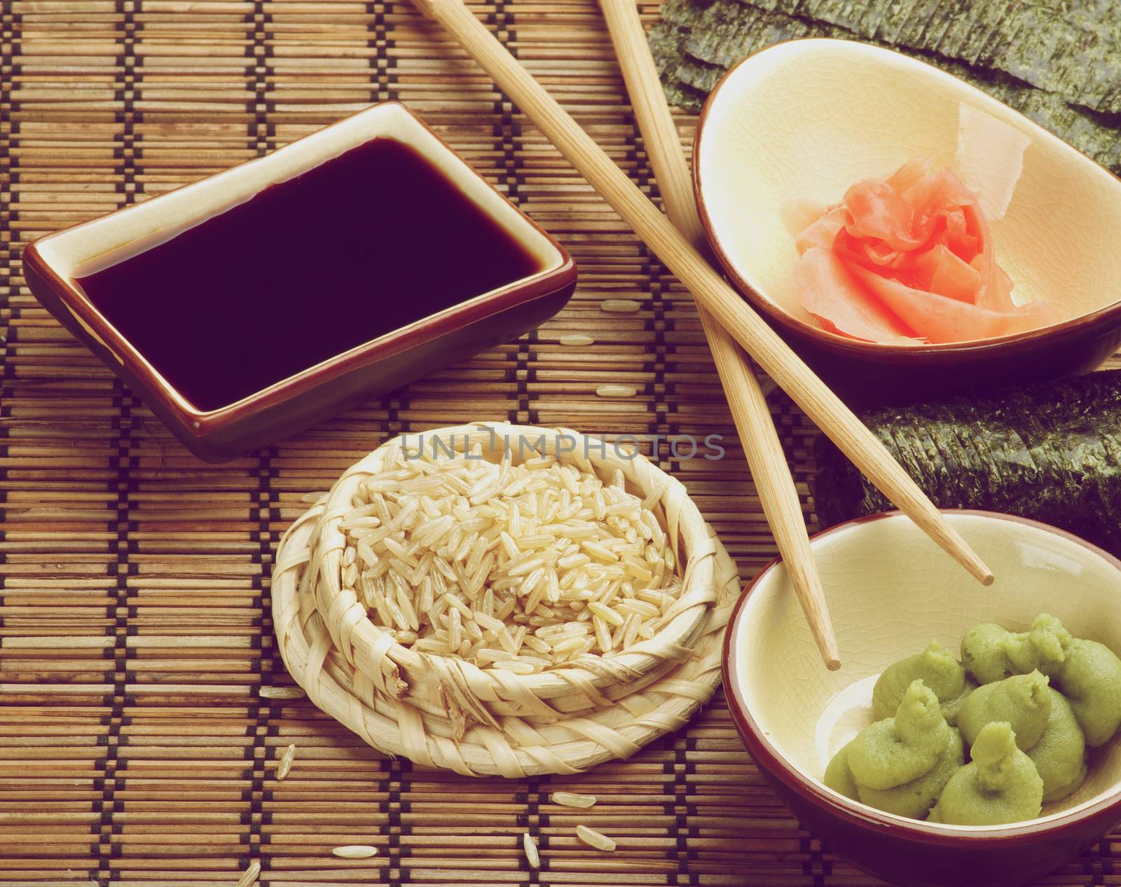 Ingredients to Preparing Sushi with Nori, Ginger, Wasabi, Rice, Soy Sauce and Two Chopsticks on Bamboo Straw Matю Retro Styled