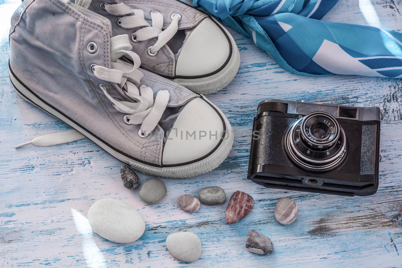 Travel still lifewith sneakers,camera and scarf on wooden board