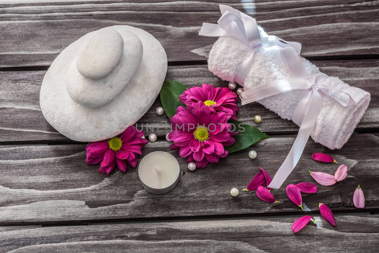 Spa concept. Rocks,candle,flowers and bath white towels on wooden background.