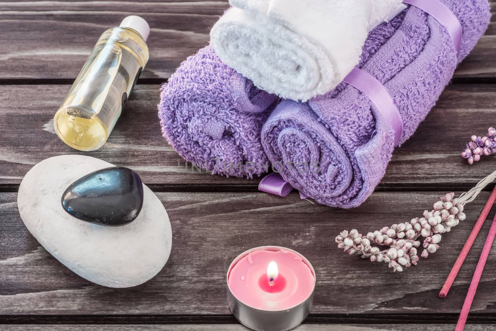 Spa concept. Lavender oil, lavender flowers and bath white and purple towels on wooden background.