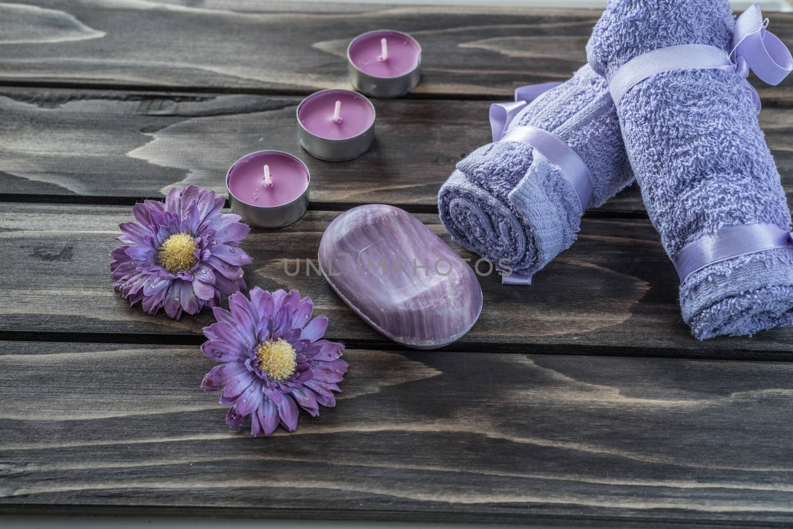 Spa concept. flowers,candles, soap and bath purple towels on wooden background