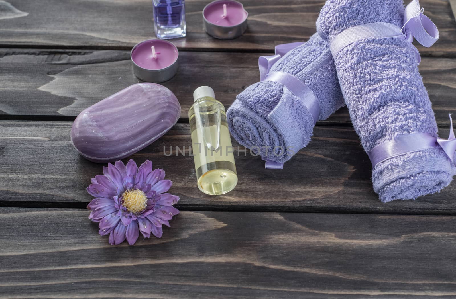 Spa concept. Lavender oil, flowers bath  and purple towels on wooden background
