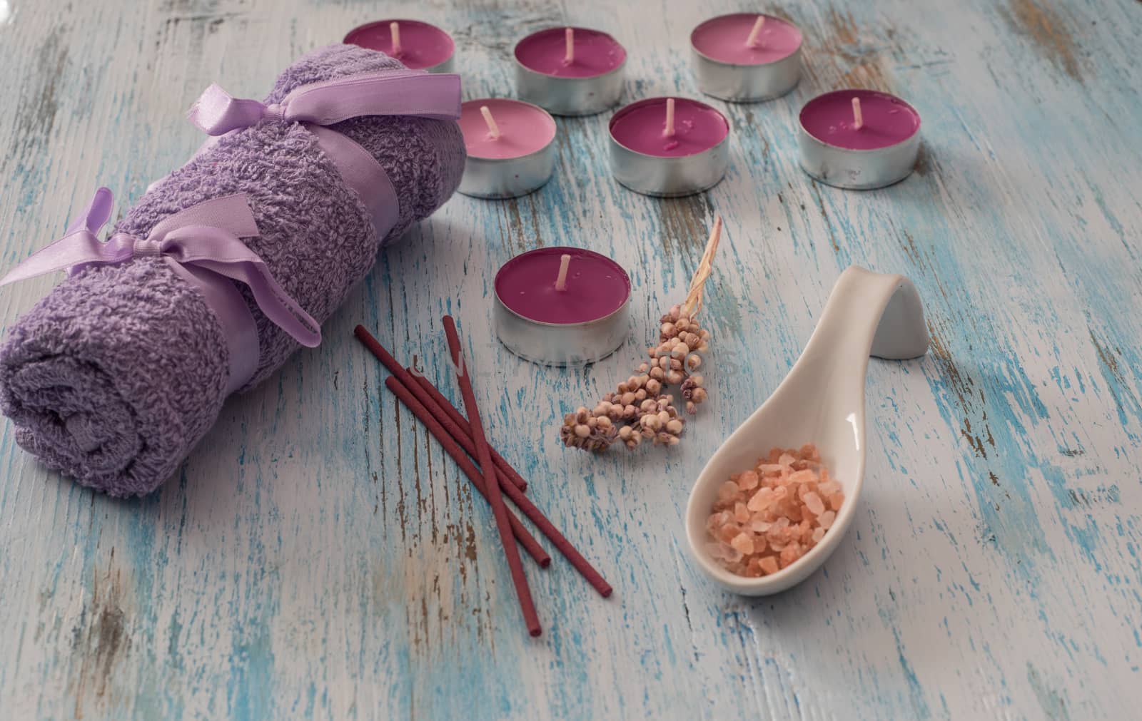 Spa concept. flower candles, aromatic salt,soap and bath purple towels on wooden background