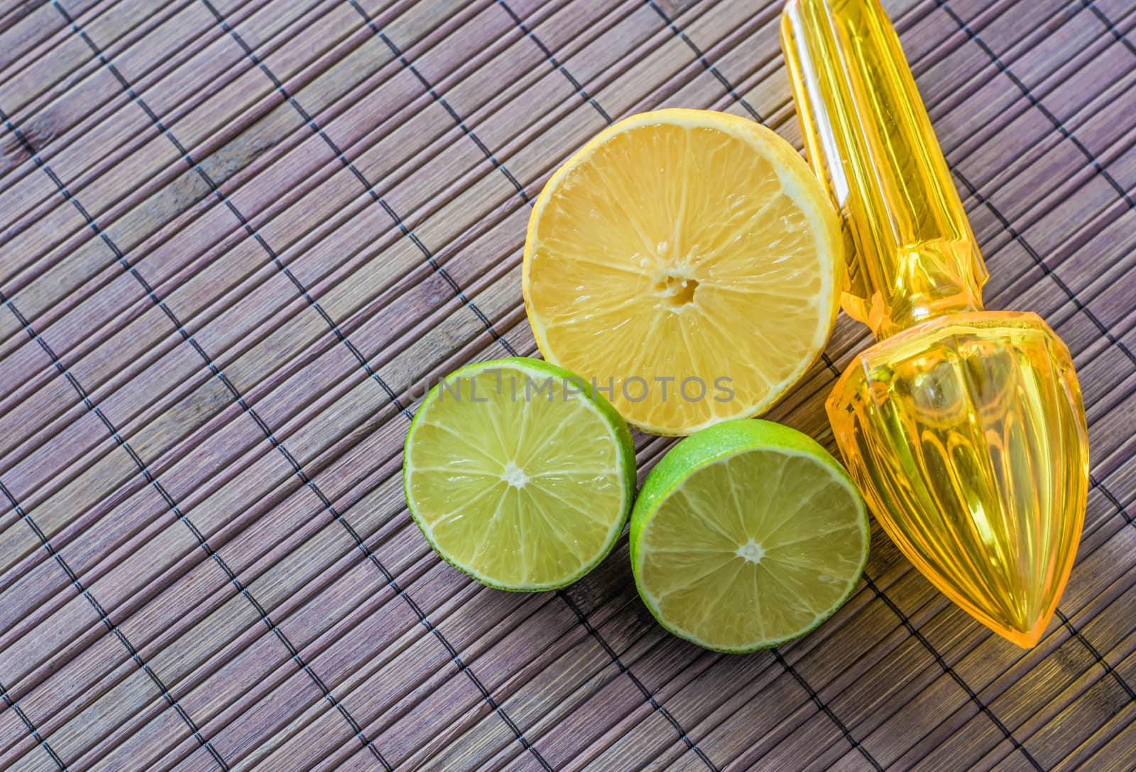 Lemon, limes and plastic juicer with handle on a wooden background