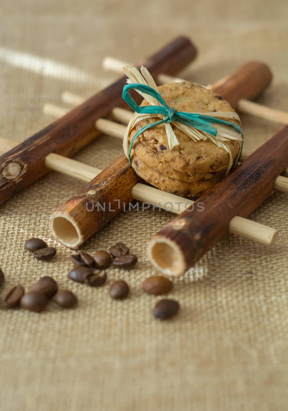 Homemade cookies and coffee beans on bamboo pad, gray background
