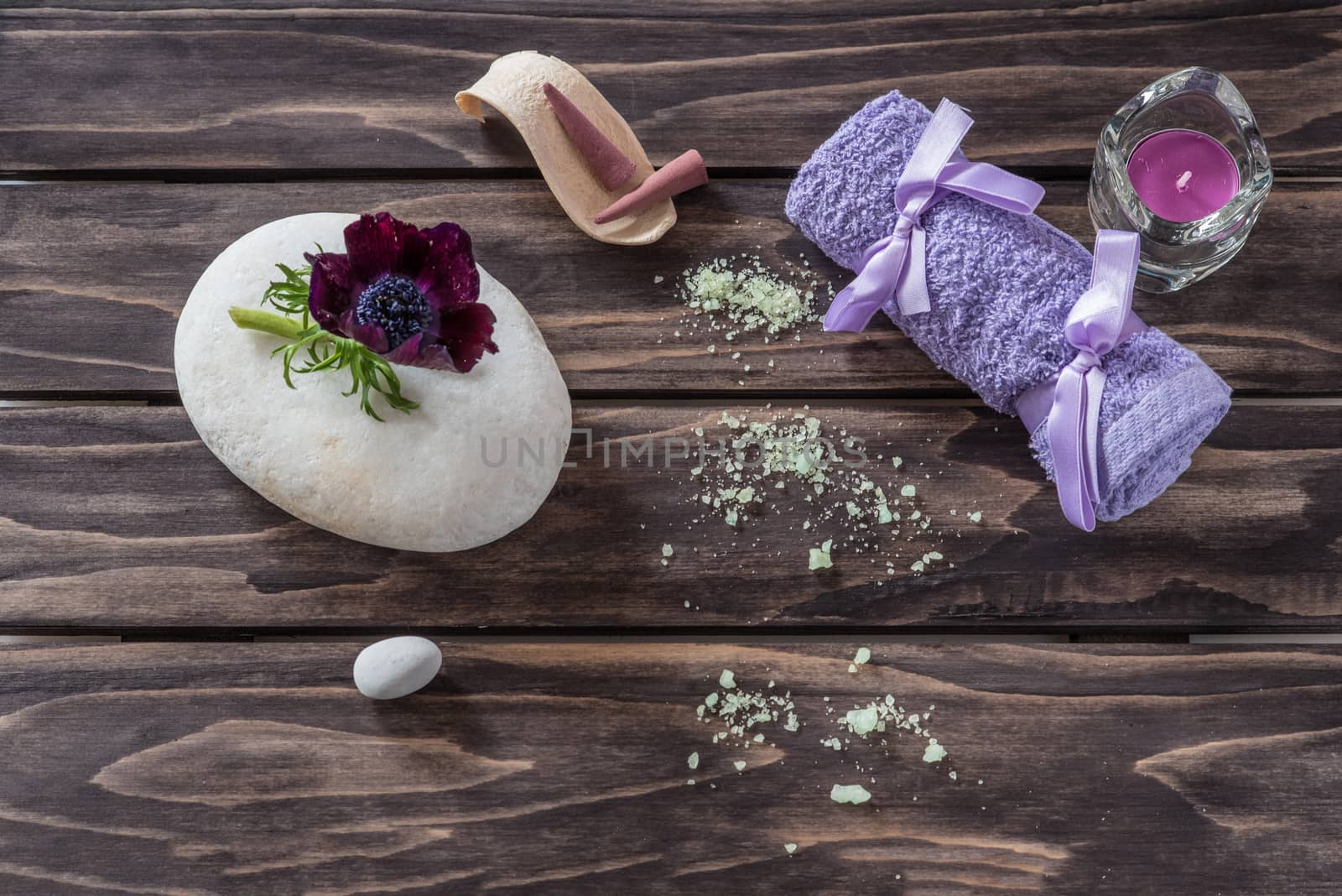 Spa concept. flowers,candles, aromatic salt and bath purple towel on wooden background