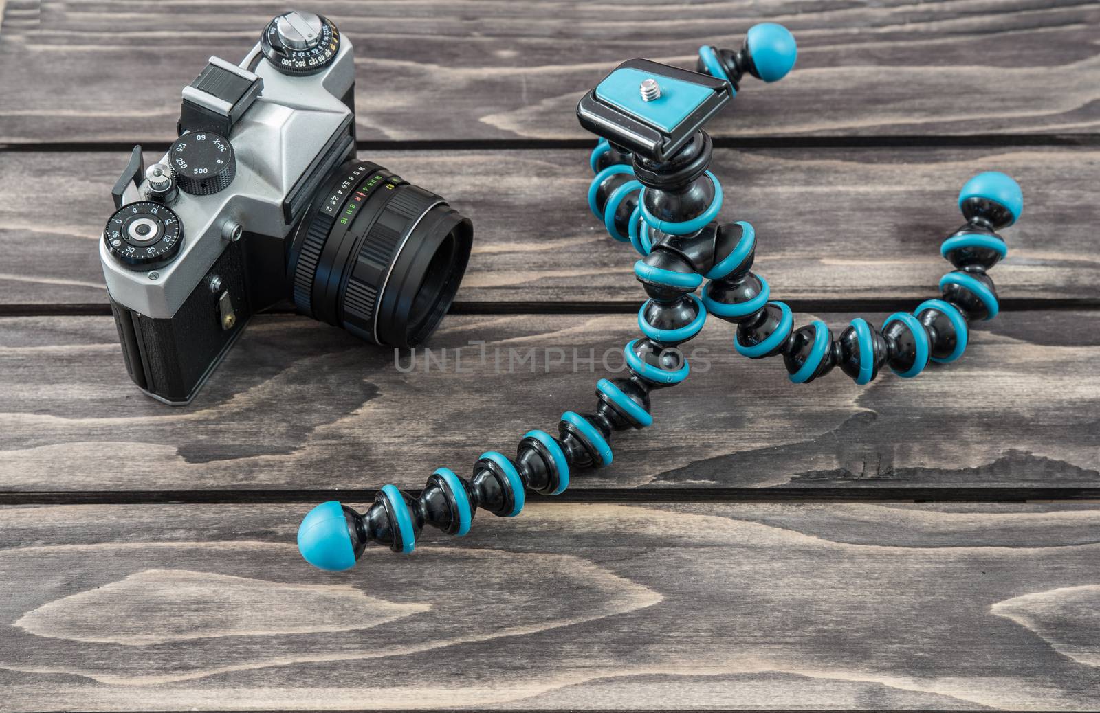 Close up view of a flexible type tripod and vintage camera on wooden background