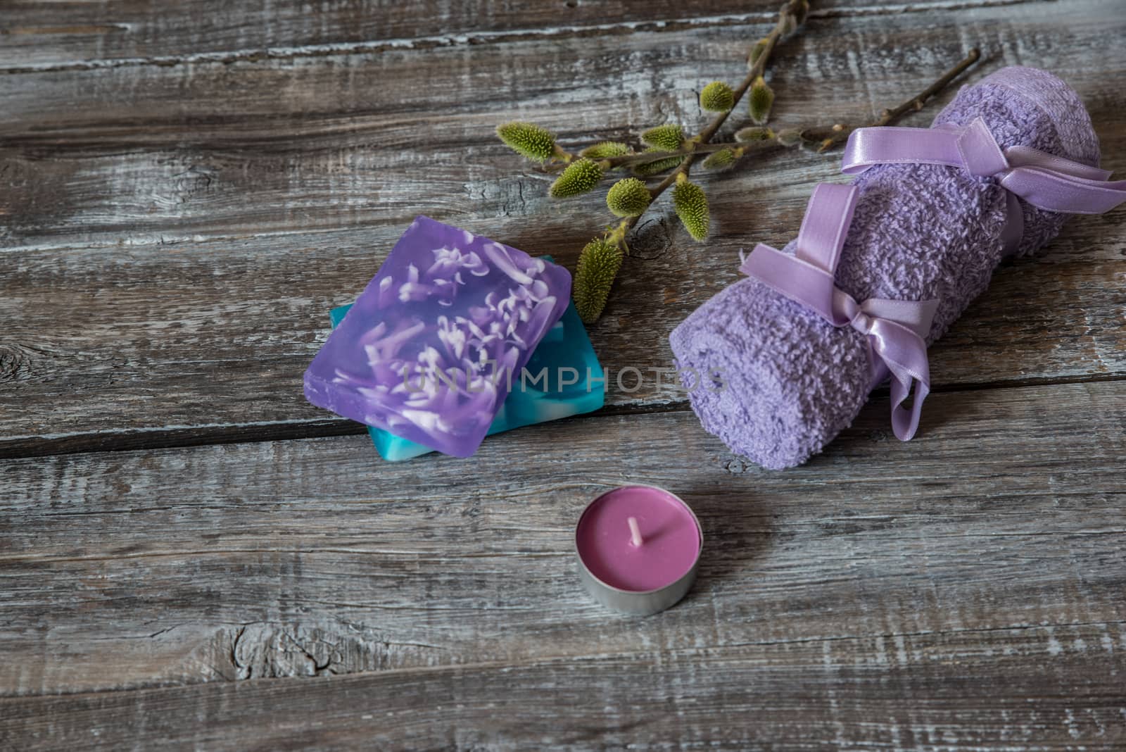 Spa concept. flowers,candles,soap and bath purple towels on wooden background