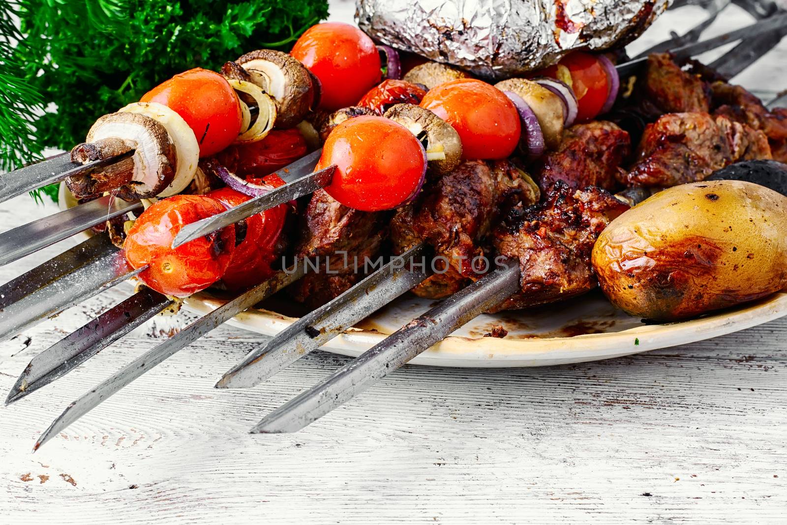 Beef cooked with vegetables on skewers and baked potatoes