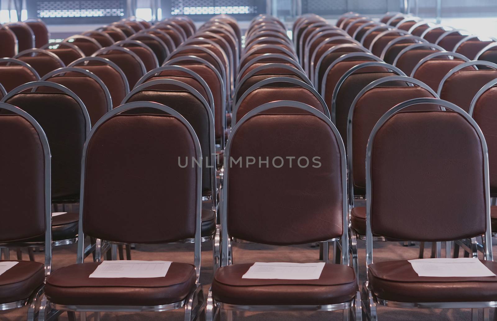 Row of brown chairs  was arranged in classroom for conference.