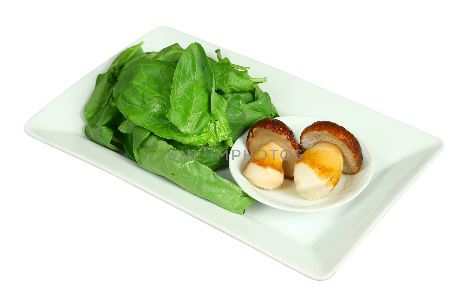 Fresh boletus mushrooms and spinach on white plate. Isolated on white.