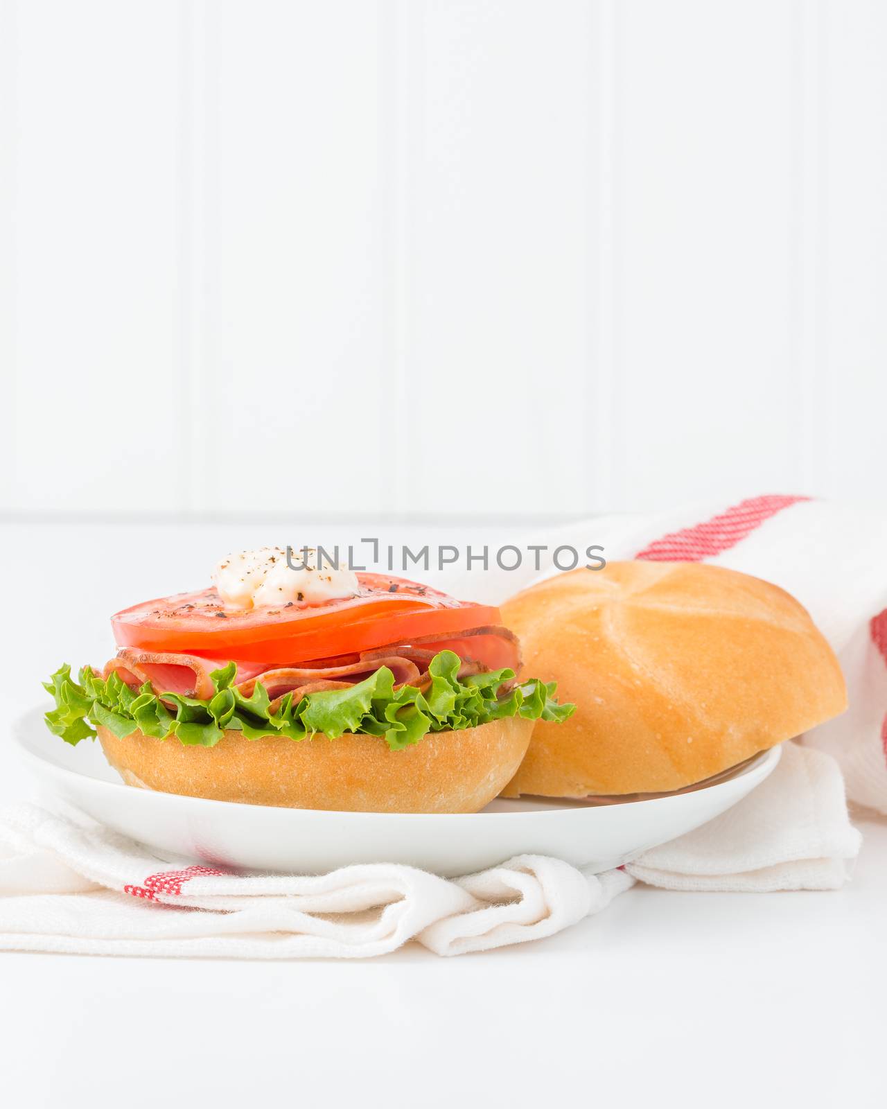 Ham and tomato sandwich on a fresh kaiser bun. 