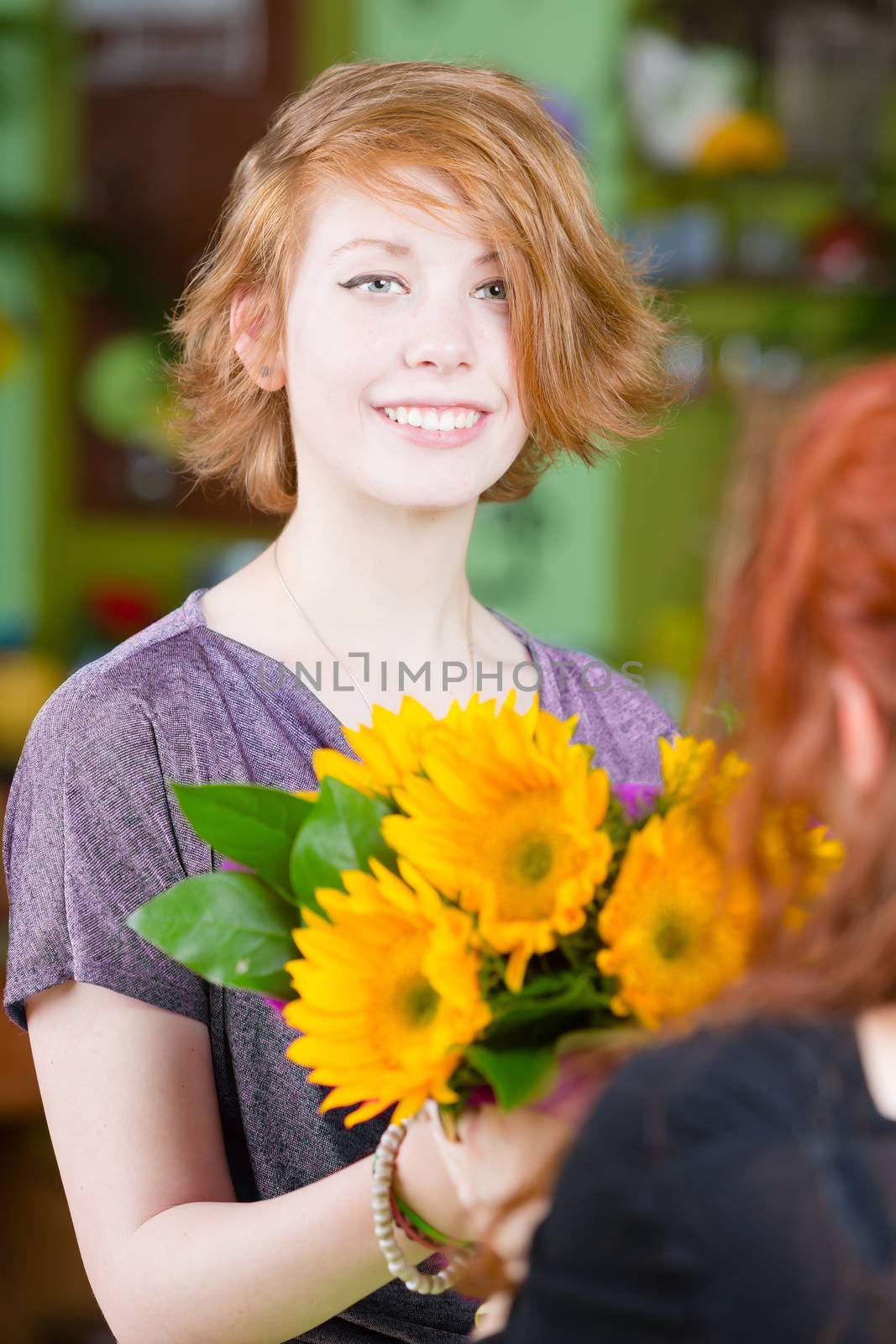Teenage red haired girl buying sunflowers at a florist shop