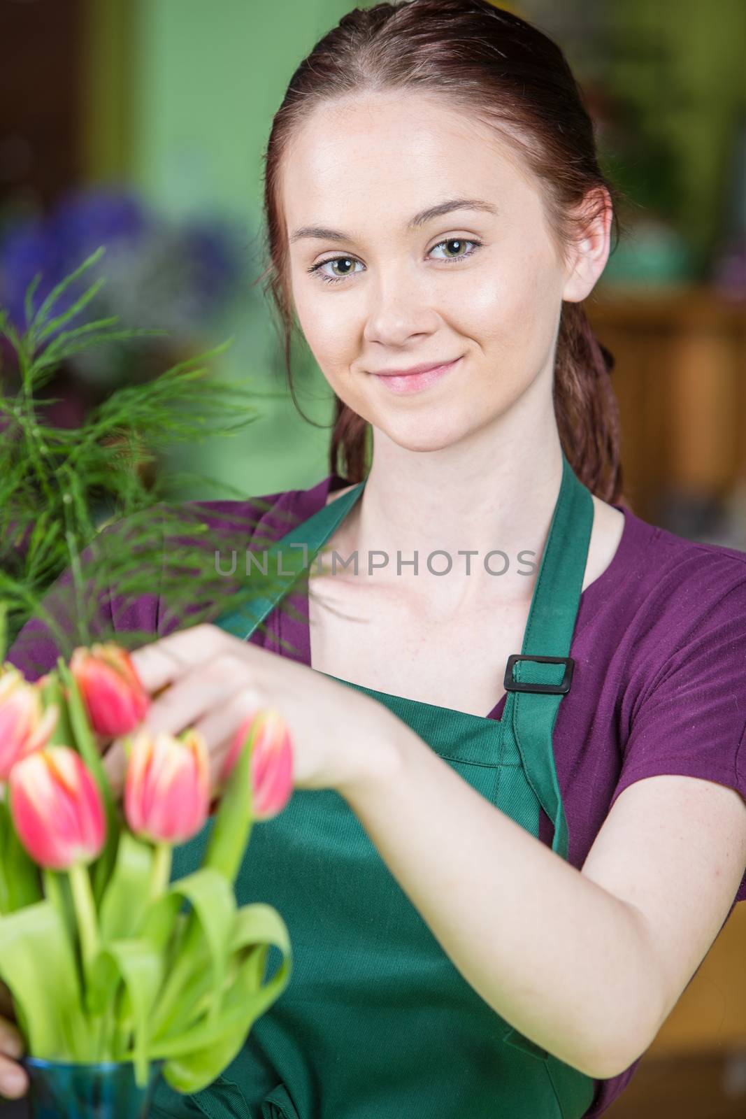 Beautiful grinning young Caucasian woman creating a tulip arrangement