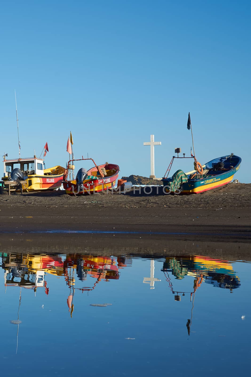 Colourful fishing boats reflected in a river in the small fishing town of Curanipe, Chile.