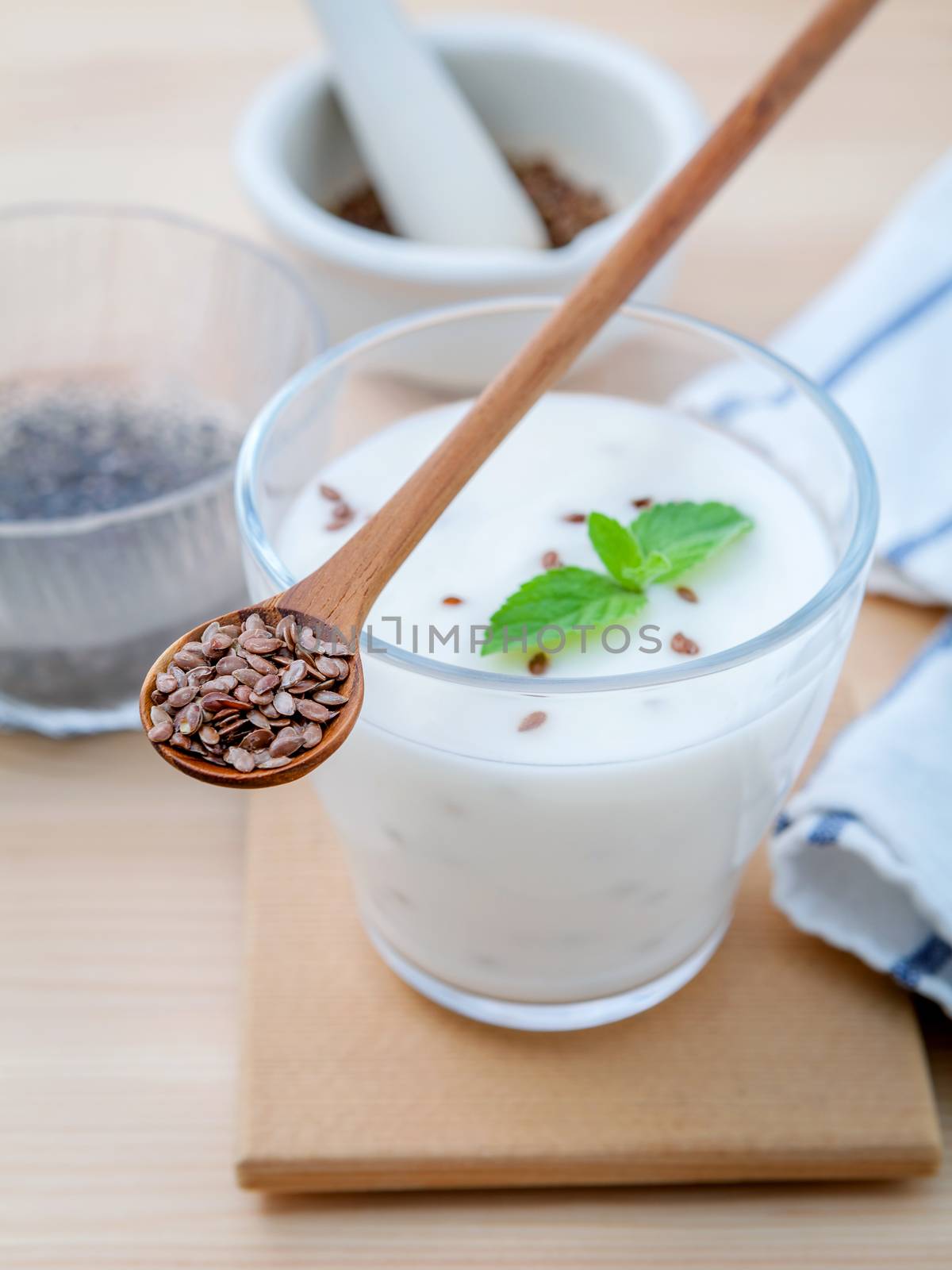 Nutritious flax seeds with glass of greek yogurt and wooden spoon for diet  meal setup on wooden background . shallow depth of field.