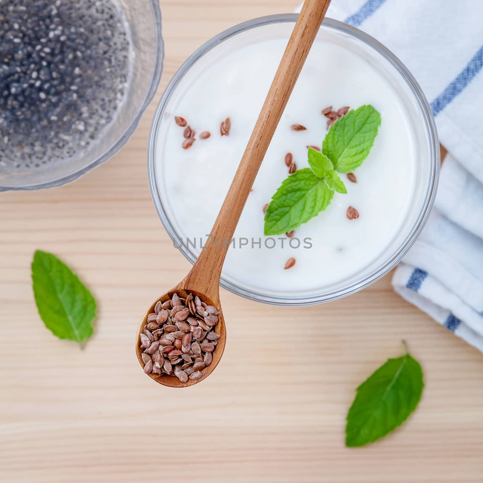 Nutritious flax seeds with glass of greek yogurt and wooden spoon for diet  meal setup on wooden background . shallow depth of field.