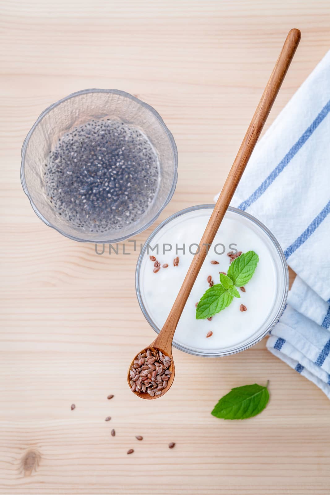 Nutritious flax seeds with glass of greek yogurt and wooden spoon for diet  meal setup on wooden background . shallow depth of field.