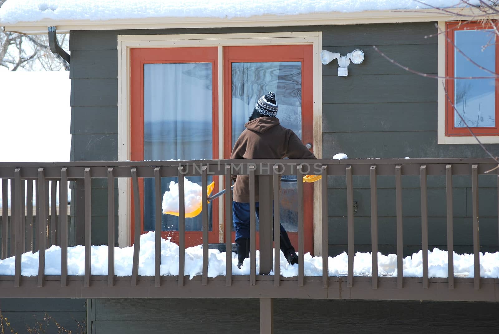 Mature female shoveling winter snow off patio deck.