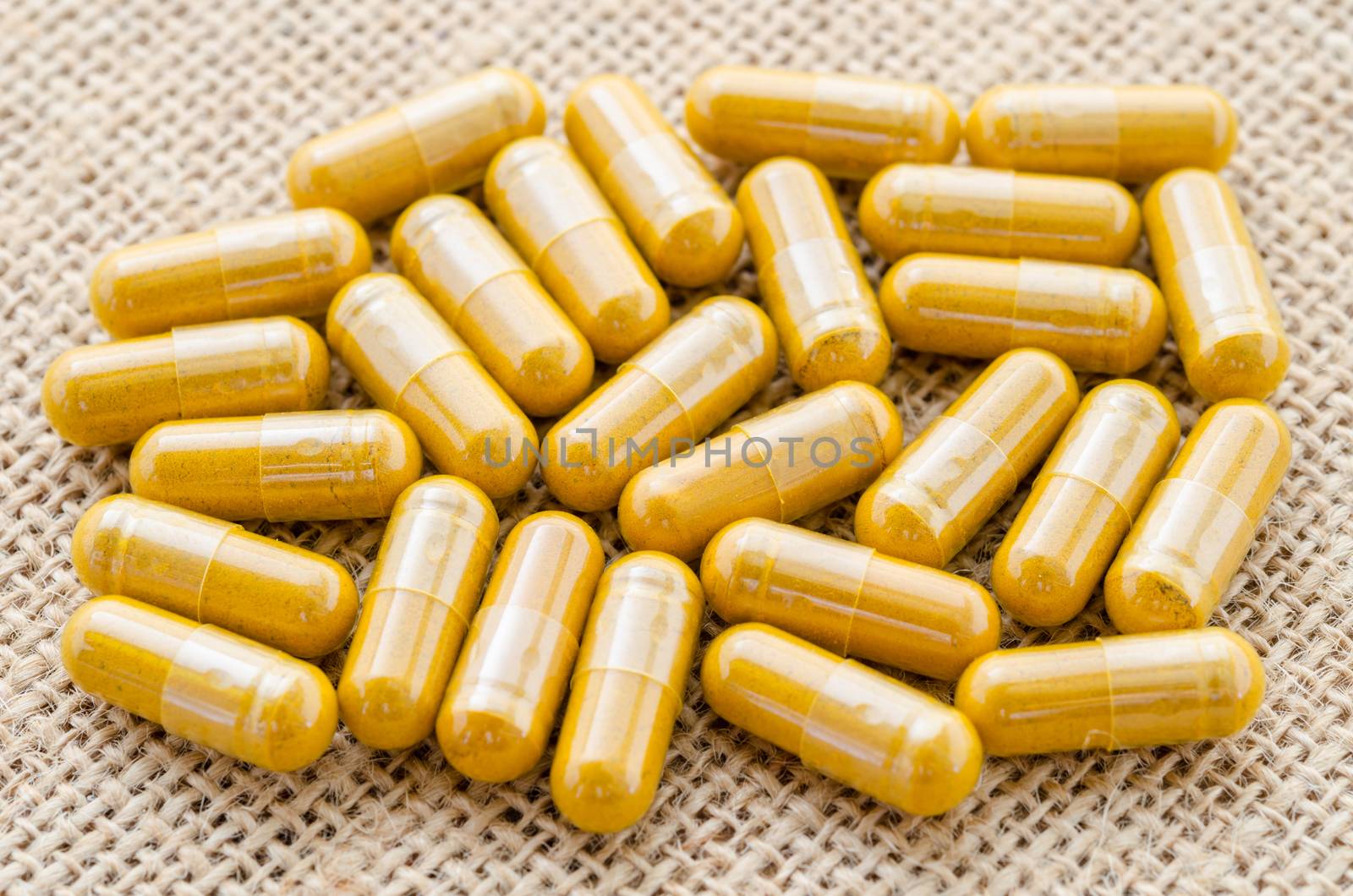 close up heap of yellow medical capsules on sack background.