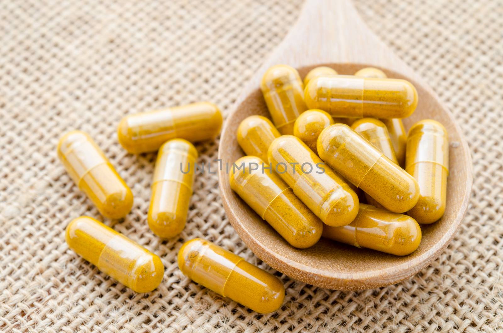 Herbal capsule. Alternative medical care on sack background.