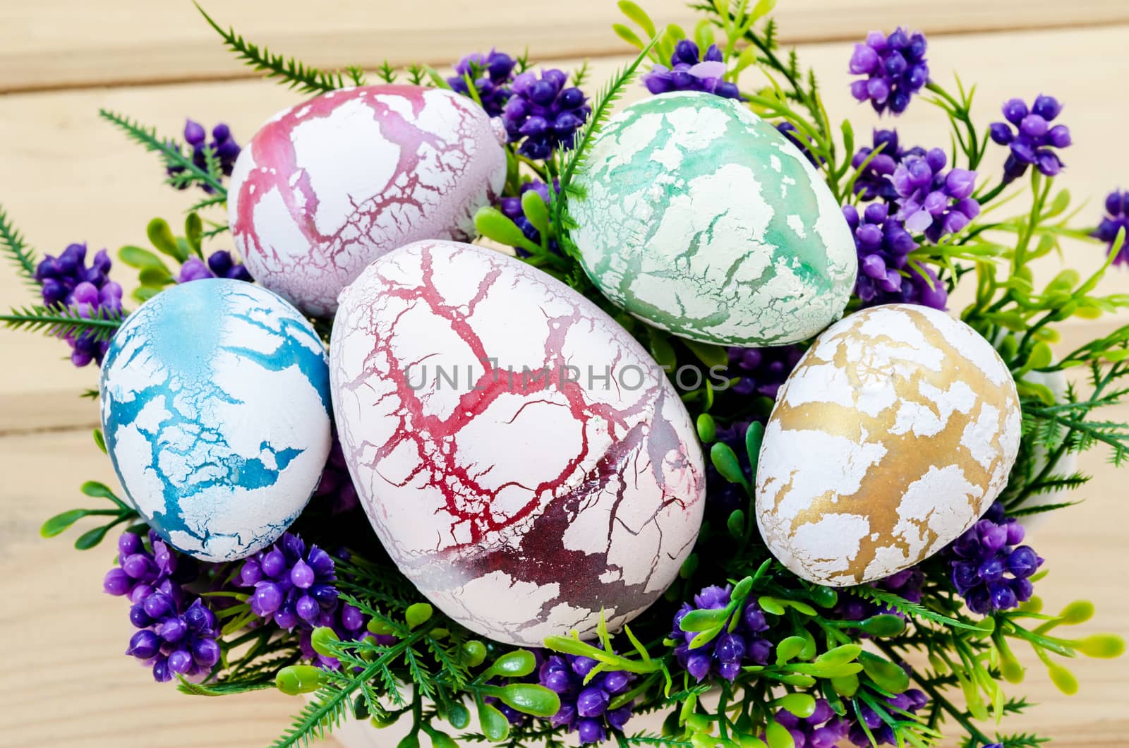 decorated easter eggs in the flower vase on wooden background.