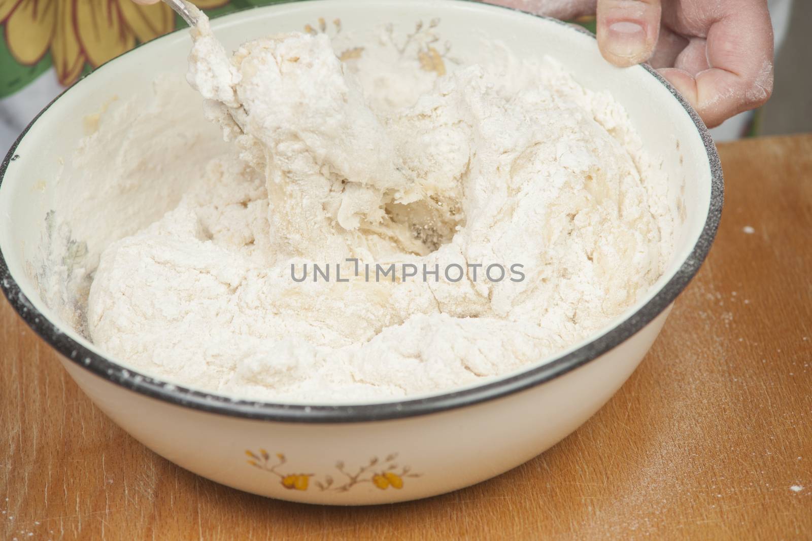 Women's hands preparing fresh yeast dough in the bowl.