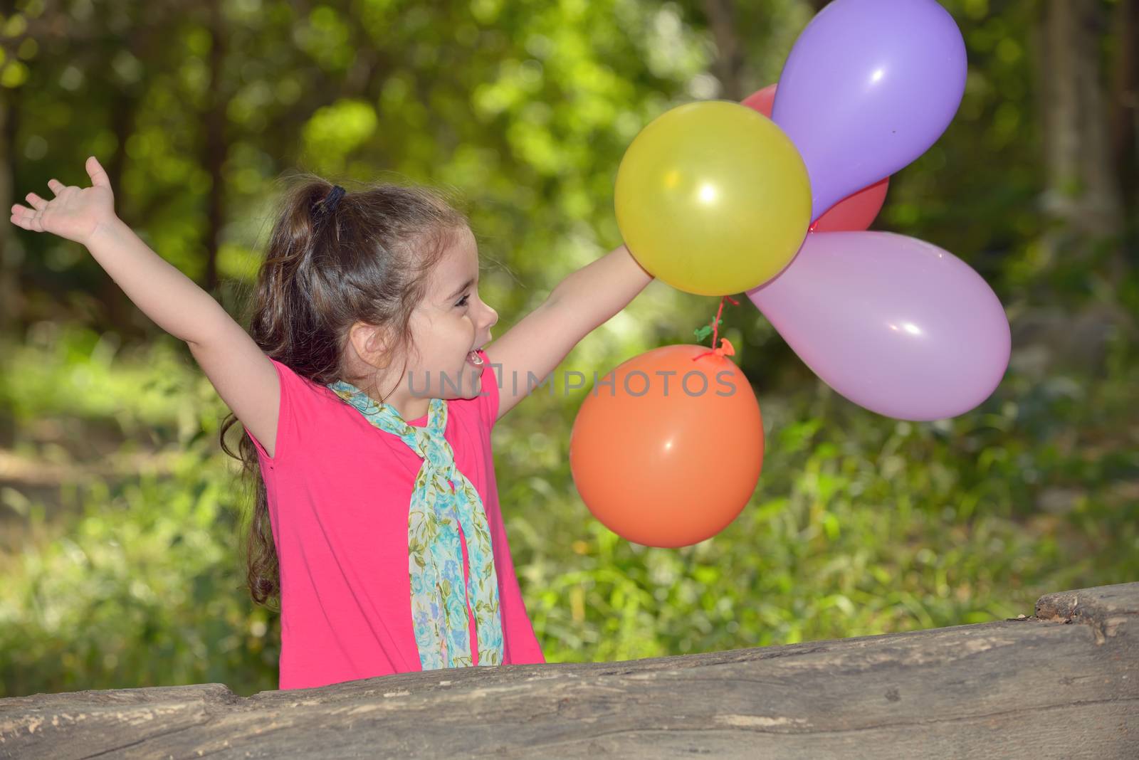 Little girl playing with balloons in forest