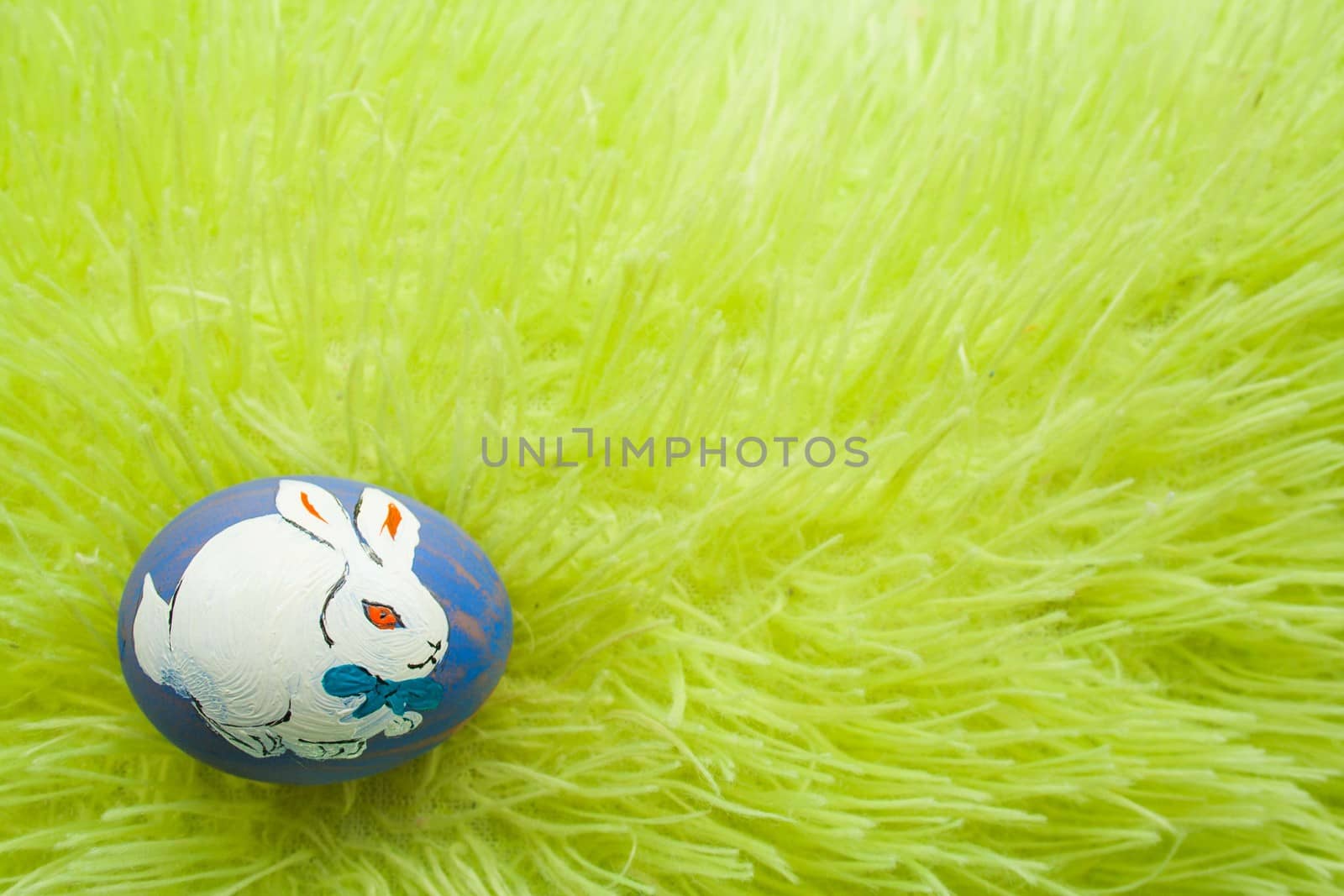 White rabbit on an Easter egg. Egg on a green grass