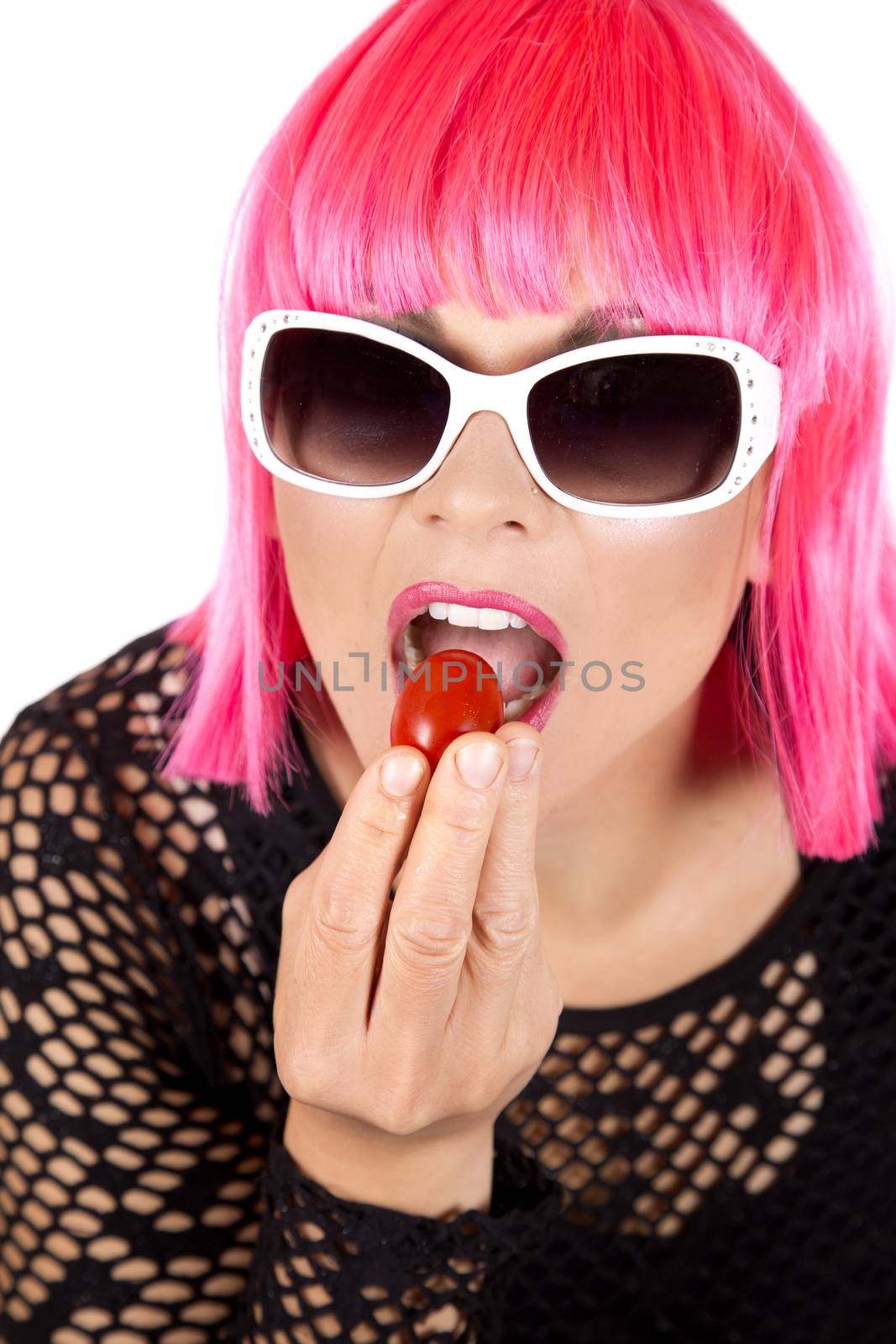 woman with pink hair eating raw vegetable