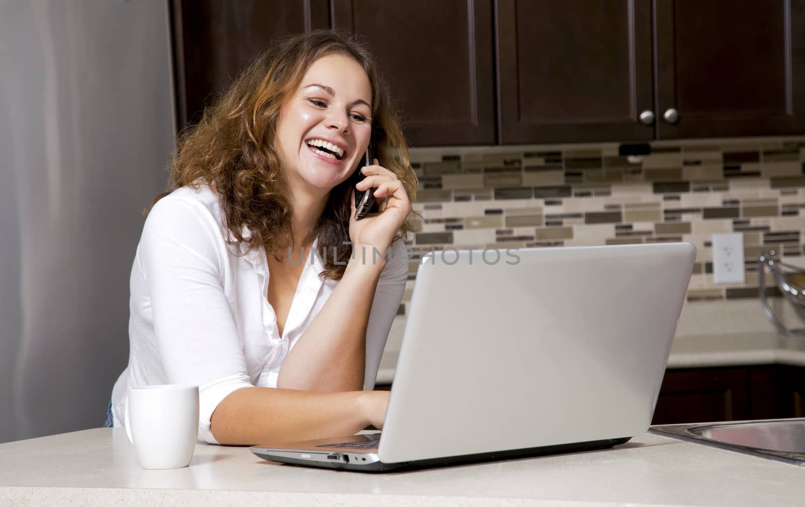 woman drinking coffee while chatting on the phone, using laptop