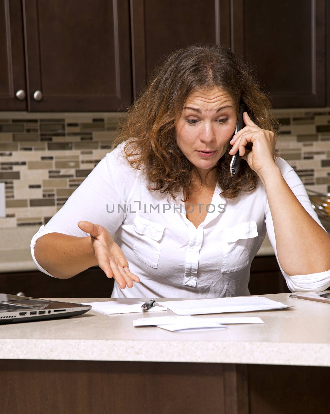 stressed woman looking at bills while sitting in the kitchen 