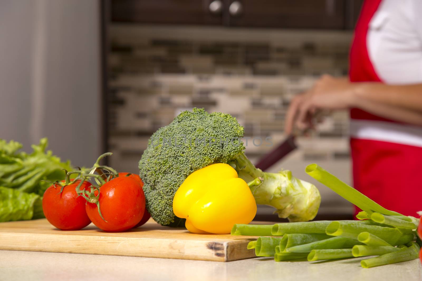 raw vegetables placed on the kitchen table with a woman in the background
