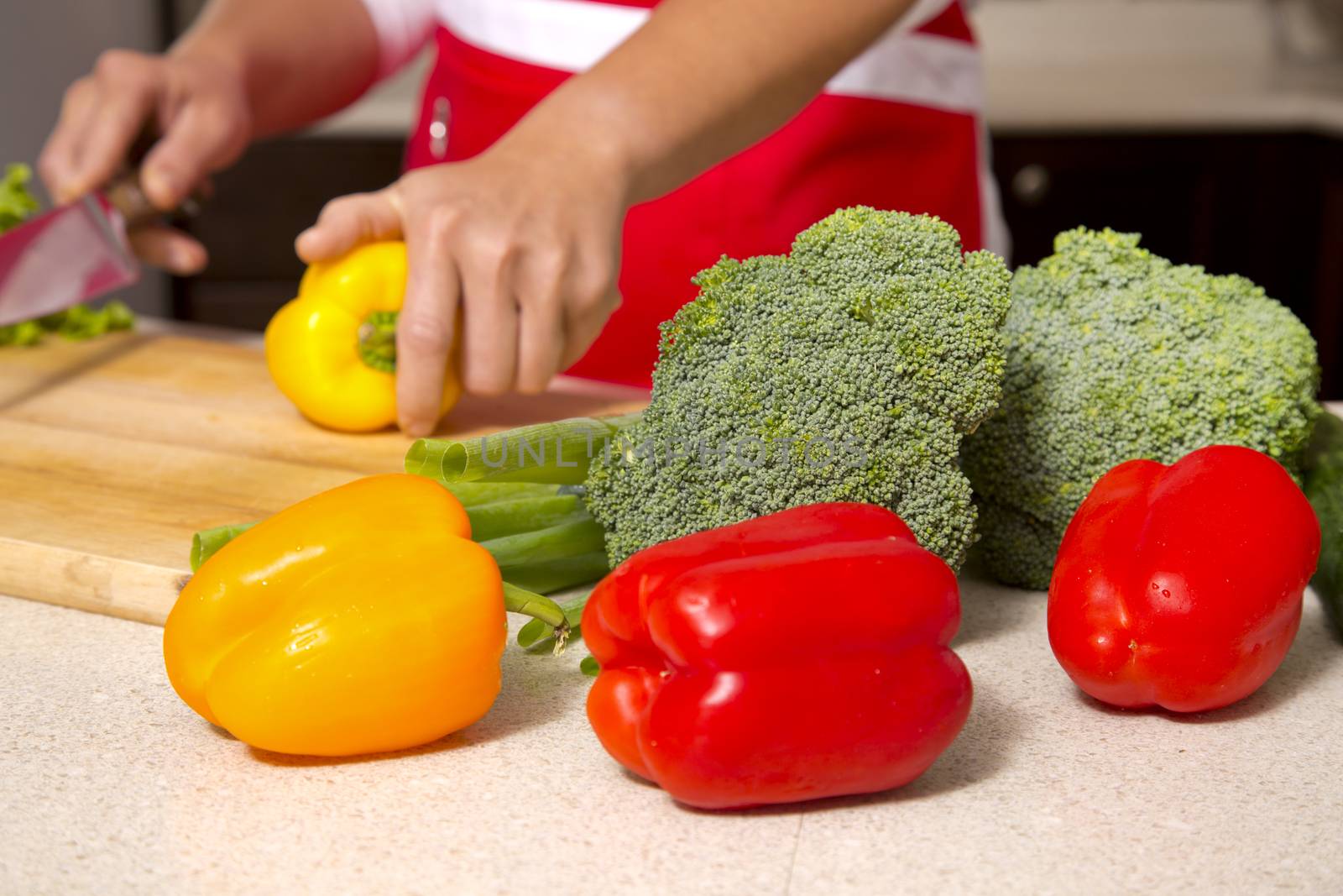 caucasian woman about to cut raw vegetables  on the kitchen